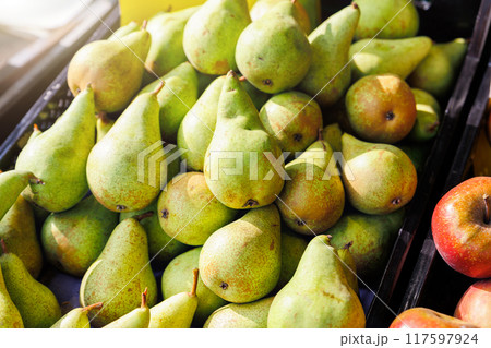 Close-up detail view many fresh juicy green local sweet farmer's pear and apples on street market retail counter on sunny day. Local domestic organic plant fruits at store. Sustainable agriculture 117597924
