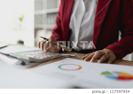 woman meticulously plans a finance audit, using a computer and calculator to review budget documents and ensure accuracy woman meticulously plans a finance audit, using a computer and calculator to review budget documents and ensure accuracy 117597934