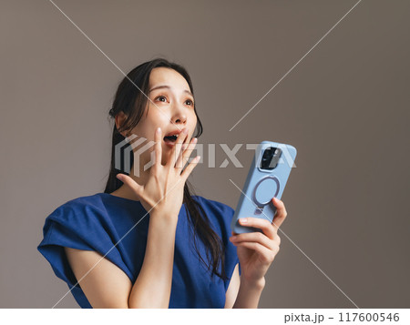 スマホを持って驚く女性 117600546