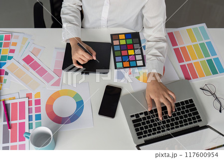 Creative Graphic Designer Working with Color Palettes and Digital Tools in Modern Office Environment Creative Graphic Designer Working with Color Palettes and Digital Tools in Modern Office Environment 117600954
