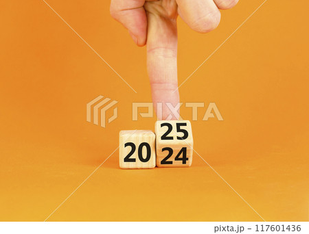 Business concept of 2025 new year symbol. Businessman turns wooden cube and changes number 2024 to 2025. Beautiful orange table orange background, copy space. Business 2025 happy new year concept. Business concept of 2025 new year symbol. Businessman turns wooden cube and changes number 2024 to 2025. Beautiful orange table orange background, copy space. Business 2025 happy new year concept. 117601436