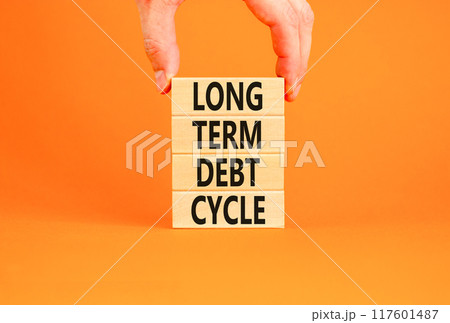 Long term debt cycle symbol. Concept words Long term debt cycle on beautiful wooden block. Beautiful orange table orange background. Businessman hand. Business Long term debt cycle concept. Copy space 117601487