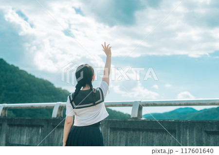 橋の上で青空に手を伸ばすセーラー服の女の子の後ろ姿 橋の上で青空に手を伸ばすセーラー服の女の子の後ろ姿 117601640