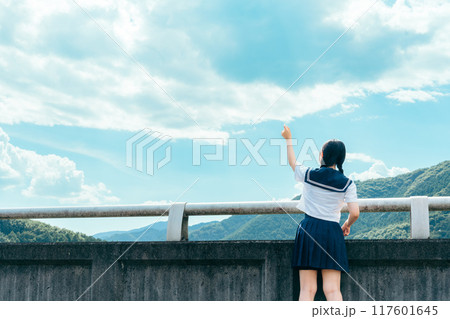 橋の上で青空に手を伸ばすセーラー服の女の子の後ろ姿 117601645