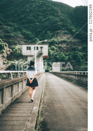 橋の上の道路を歩いてくセーラー服の女の子の後ろ姿 橋の上の道路を歩いてくセーラー服の女の子の後ろ姿 117602199