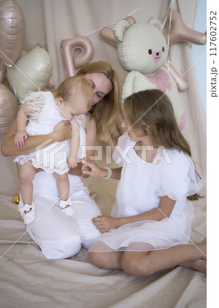 photo session on the first birthday of a baby girl with her mother and teenage sister, in pastel colors, minimalism 117602752