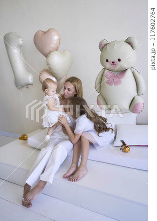 a photo session on the first birthday of a baby girl with her mother and teenage sister, in pastel colors, minimalism a photo session on the first birthday of a baby girl with her mother and teenage sister, in pastel colors, minimalism 117602764