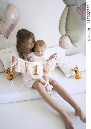 a        photo session on the first birthday of a baby girl with her  teenage sister, in pastel colors, minimalism 117602772