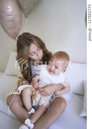 a photo session on the first birthday of a baby girl with her teenage sister, in pastel colors, minimalism a photo session on the first birthday of a baby girl with her teenage sister, in pastel colors, minimalism 117602774