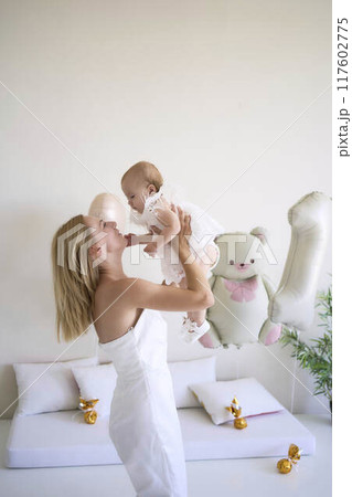 mother with a baby girl in a stylish white minimalist interior in white clothes mother with a baby girl in a stylish white minimalist interior in white clothes 117602775