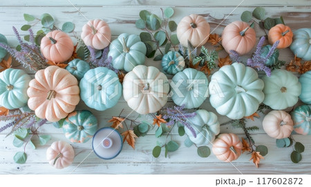 Top view of Thanksgiving decorations, pastel pumpkins, mint green leaves, candles on wooden table 117602872