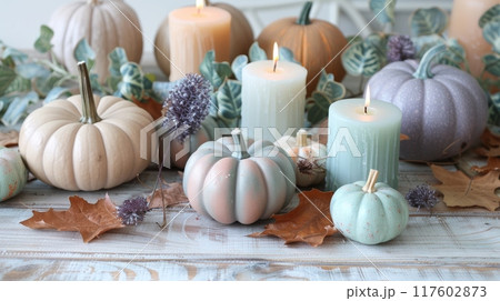 Thanksgiving decorations, pastel pumpkins, mint green leaves, and lavender candles on wooden table 117602873