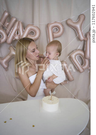 baby girl tries her first birthday cake with mom and pre-teen sister 117602941