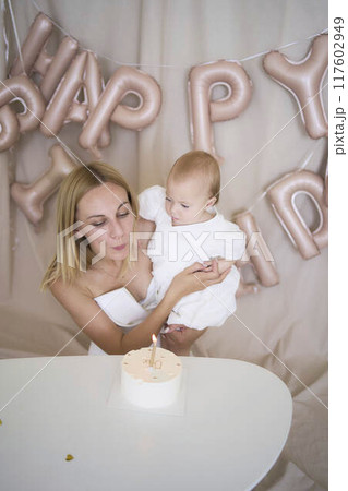 baby girl tries her first birthday cake with mom and pre-teen sister 117602949