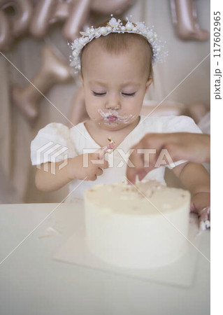 baby girl tries her first birthday cake with mom and pre-teen sister 117602965