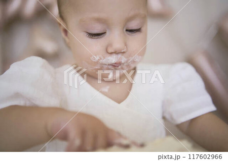 baby girl tries her first birthday cake with mom and pre-teen sister 117602966