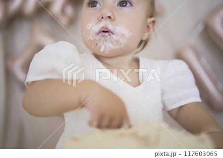 baby girl tries her first birthday cake with mom and pre-teen sister 117603065