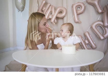 baby girl tries her first birthday cake with mom and pre-teen sister 117603081