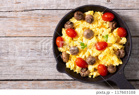 Healthy vegetarian breakfast . Scrambled eggs in pan with cherry tomatoes and parsley 117603108