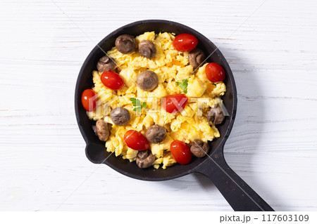 Healthy vegetarian breakfast . Scrambled eggs in pan with cherry tomatoes and parsley Healthy vegetarian breakfast . Scrambled eggs in pan with cherry tomatoes and parsley 117603109