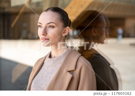 Young beautiful woman wearing coat walking in the city centre of Prague, Europe 117603162
