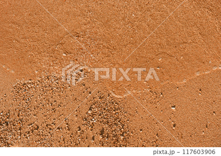 Close-up of the texture of sand and water waves on a beach. 117603906