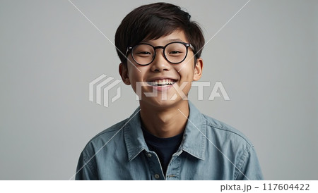 Portrait of a happy Asian schoolboy teenager with glasses on a solid gray background. Back to school, correction of pupil kid eyesight. AI generated 117604422