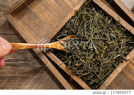 Green tea in wooden box and barrel on wooden board Green tea in wooden box and barrel on wooden board 117605077