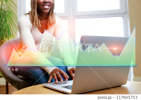 A woman is sitting in front of a laptop with a graph on the screen A woman is sitting in front of a laptop with a graph on the screen 117605753