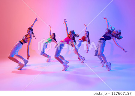 With grace and intensity, dancers bring their choreography to life on stage in neon light against gradient pink background. With grace and intensity, dancers bring their choreography to life on stage in neon light against gradient pink background. 117607157