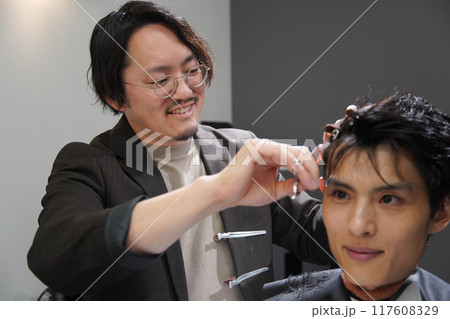 髪を切る男性美容師 117608329