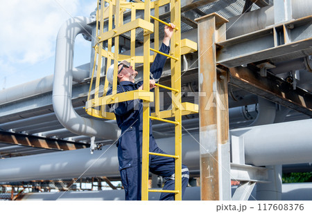 Factory engineer or technician worker climb up on stair of petrochemical gas pipeline to work or maintenance in workplace. Factory engineer or technician worker climb up on stair of petrochemical gas pipeline to work or maintenance in workplace. 117608376