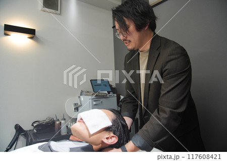 髪を洗う男性美容師 117608421