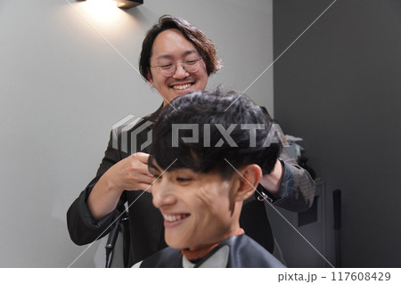 髪を切る男性美容師 117608429