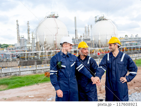 Factory engineer or technician workers stand and join hands together in front of tank of refining and petrochemical factory with day light. Factory engineer or technician workers stand and join hands together in front of tank of refining and petrochemical factory with day light. 117608921