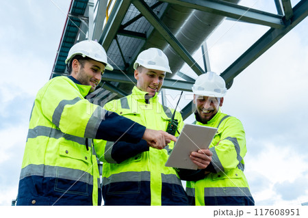 Close up view factory engineer or technician workers use tablet to discuss about work together and stay under petrochemical pipeline with day light. Close up view factory engineer or technician workers use tablet to discuss about work together and stay under petrochemical pipeline with day light. 117608951