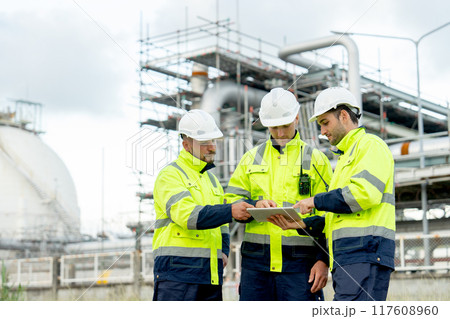 Wide shot engineer or technician workers stand in front of  petrochemical factory and use tablet to discuss their work. 117608960