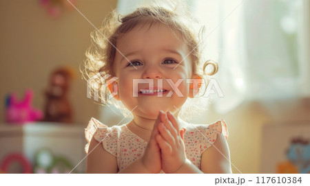 Joyful toddler clapping hands with a beaming smile. 117610384