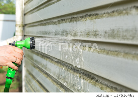 Cleaning algae and mold from vinyl siding of house with pressure spray jet Cleaning algae and mold from vinyl siding of house with pressure spray jet 117610465