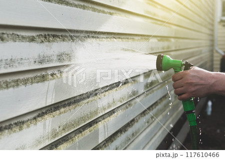 Cleaning algae and mold from vinyl siding of house with pressure spray jet Cleaning algae and mold from vinyl siding of house with pressure spray jet 117610466
