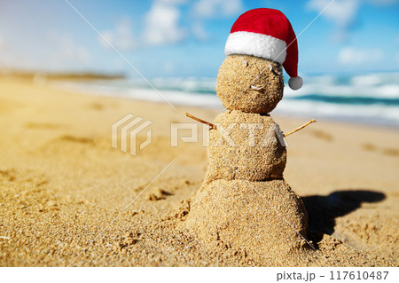 Caribbean Christmas Snowman with Santa Claus Hat made out of sand on sandy beach. Holiday vacation. New Year travel greeting card Caribbean Christmas Snowman with Santa Claus Hat made out of sand on sandy beach. Holiday vacation. New Year travel greeting card 117610487