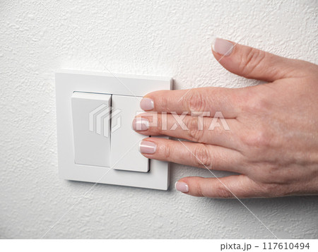 Woman switch on the light at home. Female hand push button on wall Woman switch on the light at home. Female hand push button on wall 117610494