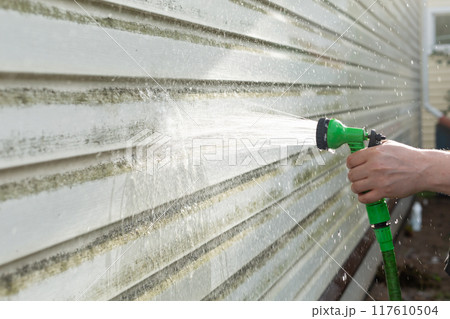 Cleaning algae and mold from vinyl siding of house with pressure spray jet Cleaning algae and mold from vinyl siding of house with pressure spray jet 117610504