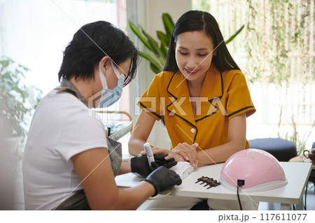 Enjoying Manicure Session While Relaxing at Salon 117611077