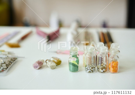 Arranging Bottles with Colorful Beads on White Table 117611132