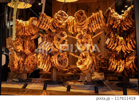 Tasty handmade pretzels with different toppings hanging for sale in marketplace, delicious bakery at street cafe 117611419