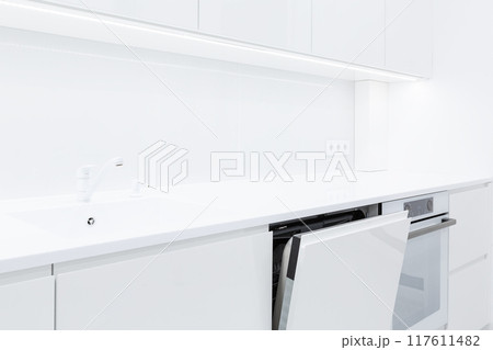 Modern white kitchen interior with acrylic countertop and built in stone sink and opened door of washing machine, Modern white kitchen interior with acrylic countertop and built in stone sink and opened door of washing machine, 117611482