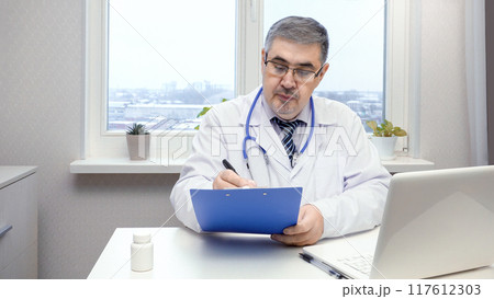 Male Doctor Working on Computer in Office 117612303