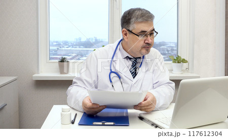 Male Doctor Working on Computer in Office 117612304