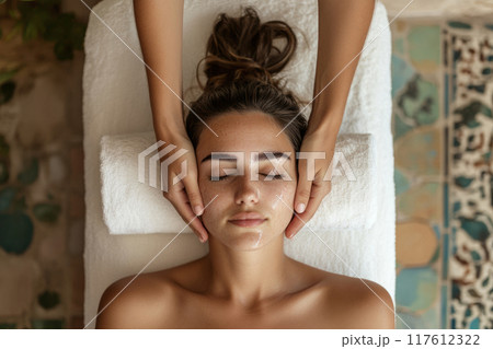 Woman getting a face massage on a massage table 117612322